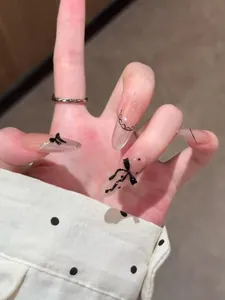 Detail of long almond press-on nails with 3D black bows and lace dot patterns