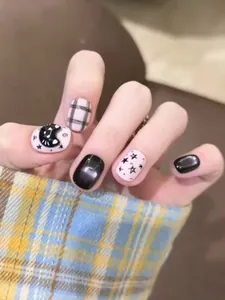 Nahaufnahme von schwarzen und rosa Kunstnägeln mit Katzenmotiven und Karomuster