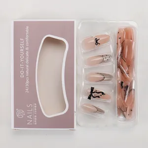 Detail of almond press-on nails featuring French tips, black polka dots and 3D bow accents