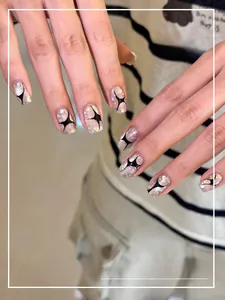 Detailed view of short trapezoidal nails with silver glitter and black star patterns