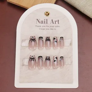 Short trapezoid press-on nails with black French tips, 3D bows, and rhinestone accents