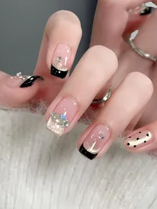 Close-up of black gold French press-on nails with champagne glitter and rhinestones