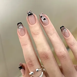 Close-up of French cat-eye press-on nails with black bows and sparkling silver rhinestones
