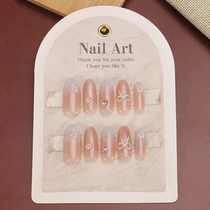 Press-on nails with pink gradient, white bows, and pearls on a display card