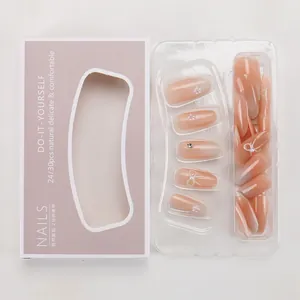 Detail of pink gradient press-on nails with pearls, bow charms, and branded packaging