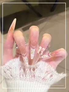 Detail of pink gradient press-on nails with 3D bows and floral French tip pattern