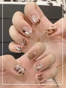 Detail of short press-on nails with leopard print, stars and 3D bowknot accents