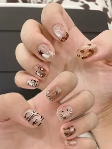 Detail shot of leopard print press-on nails with cartoon cat and bow design accents