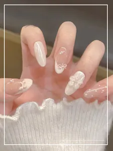 Detail of handmade press-on nails featuring white bows, pearls and 3D floral designs