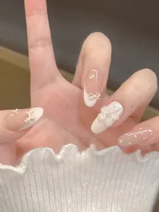 Detail of pink press-on nails featuring 3D bow, floral relief, and pearl accents