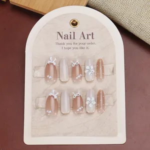Detail of handmade press-on nails featuring 3D bows, pearls and floral motifs in nude pink