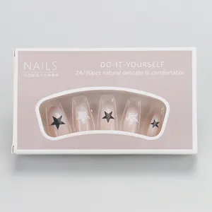 Macro detail of nude gradient press-on nails with black stars and 3D pearls in box