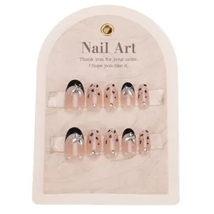Press-on nails featuring black French tips, leopard print, and silver rhinestone bows