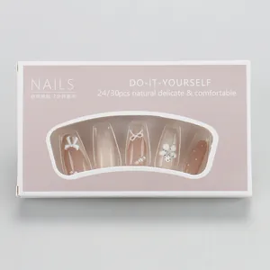 Detail of pink press-on nails featuring 3D white bows, pearls and floral accents