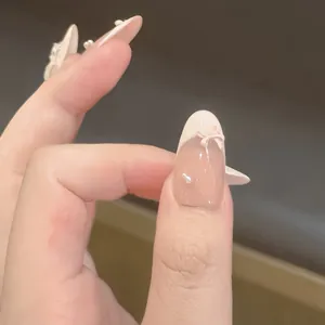 Handmade press-on nails featuring white 3D bows and pearls on a nude French base