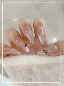 Detailed view of nude gradient press-on nails with 3D cherry beads and glossy finish