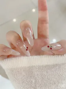Detailed view of long almond press-on nails with nude gradient and 3D cherry accents