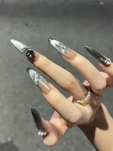 Detail of long almond silver cat eye nails with 3D black rhinestones and bow charms