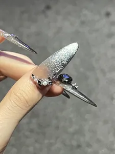 Macro view of long stiletto press-on nails with silver glitter and bow rhinestones