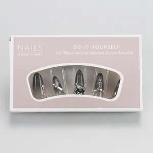 Detail of silver black gradient press-on nails set with rhinestones and bow in box