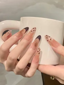 Gros plan d'ongles longs en amande avec motifs léopard et pointes de style français marron