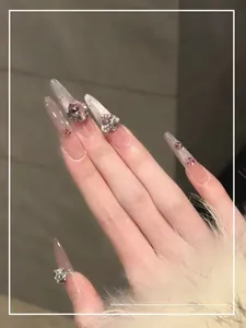 Close-up of handmade almond press-on nails with 3D rhinestones and silver glitter gradient