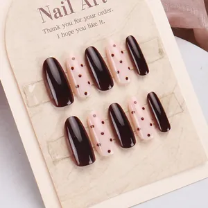 Dettaglio di unghie finte fatte a mano ovali marrone scuro e rosa chiaro con pois