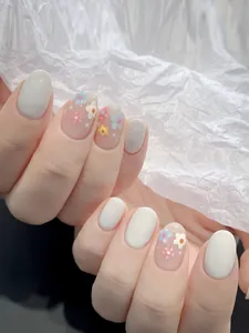Détail de faux ongles ovales courts avec motifs floraux et tons de couleurs pastel