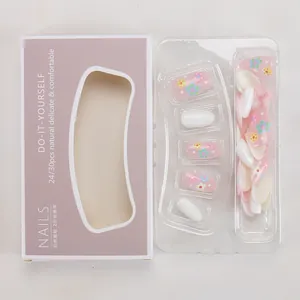 Détail des faux ongles à fleurs roses présentés dans un emballage violet élégant