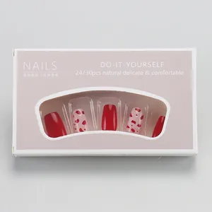 Short press-on nails set with red hearts and dots in a pink display window box packaging