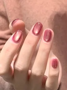 Detail von kurzen ovalen Kunstnägeln mit rosa Farbverlauf und Katzenauge-Glitzereffekt