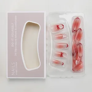 Macro shot of red gradient press-on nails with bow details and retail packaging box
