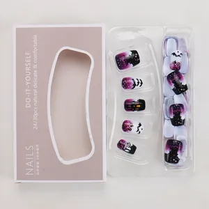 Short Halloween press-on nails with purple castle and bat designs in pink packaging