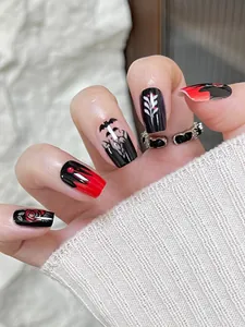 Primer plano de uñas góticas de Halloween con rosas rojas y diseños de murciélagos