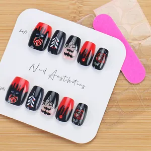 Detalle macro de uñas postizas góticas de Halloween con rosas rojas, murciélagos y kit