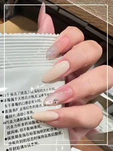 Detail view of oval nude pink press-on nails with glitter and rhinestone accents