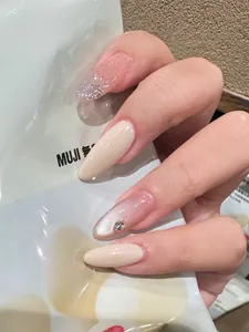 Detail of almond-shaped press-on nails with glitter gradient, cat-eye finish, and rhinestone