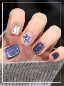 Detail of short dark purple cat-eye press-on nails with silver glitter and star accents