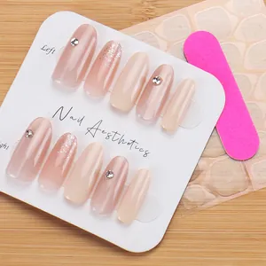 Close-up of nude pink press-on nails with rhinestones, glitters and nail file kit