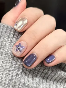 Detail of short purple glitter press-on nails with silver metallic star accents and rhinestones