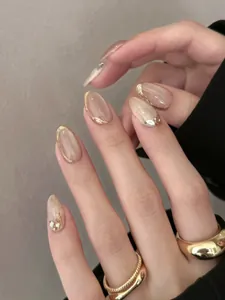 Detail of short oval nude press-on nails with cat-eye texture and rhinestone accents