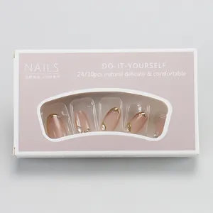 Detail of nude pink cat-eye press-on nails with gold French tips and rhinestones