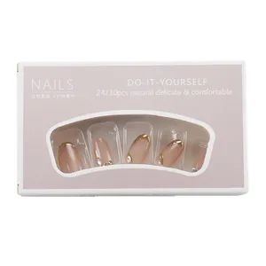 Short oval nude pink press-on nails with gold French tips and sparkling rhinestone accents