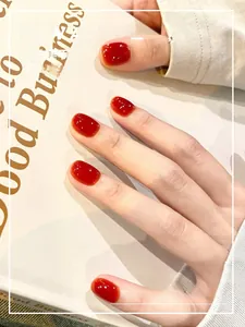 Glossy cherry red press-on nails shown on hands holding a book for a chic autumn look