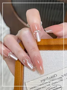 Detail of nude pink trapezoid press-on nails with pearl accents and rhinestone charms
