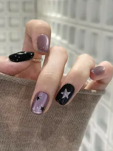 Detailed macro view of purple cat eye and black press-on nails with silver star glitter