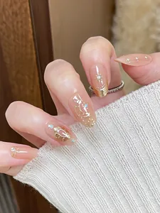 Close-up of galaxy themed press-on nails with gold sun and moon patterns on pink base
