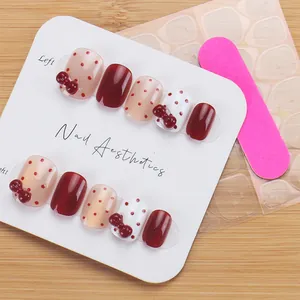 Detail of wine red bow press-on nails set with polka dots and essential application kit