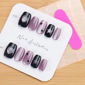 Close-up of black and purple cat-eye press-on nails with silver star details and gems