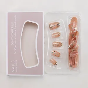 Flat lay of pink press-on nail kit with gold lines and rhinestones in retail packaging